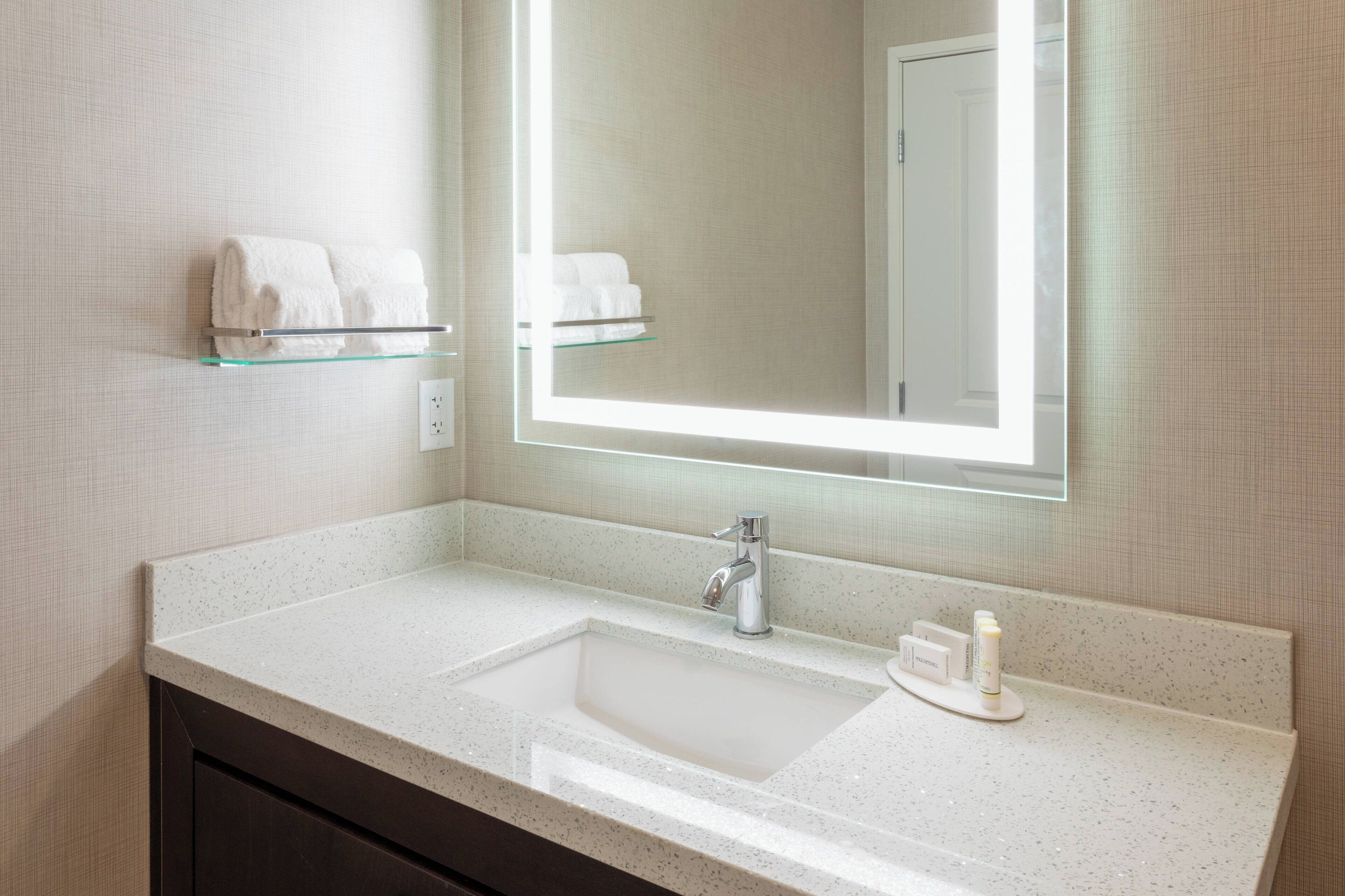 Une salle de bain moderne avec un grand miroir, un lavabo et deux porte-serviettes.