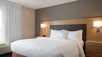 Habitación de hotel con una cama grande, dos mesitas de noche con lámparas, una ventana con cortinas y un aire acondicionado de pared.