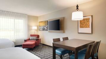 Een hotelkamer met een bed, een bureau, een stoel, een televisie en een lamp.