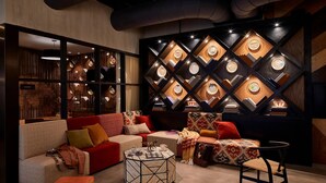 A modern lounge area with a sofa, ottoman, and a coffee table. - Moxy Chattanooga Downtown (Chattanooga)