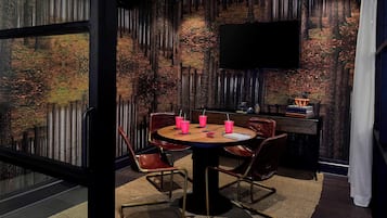 A modern dining area with a round table, chairs, and a television mounted on the wall.