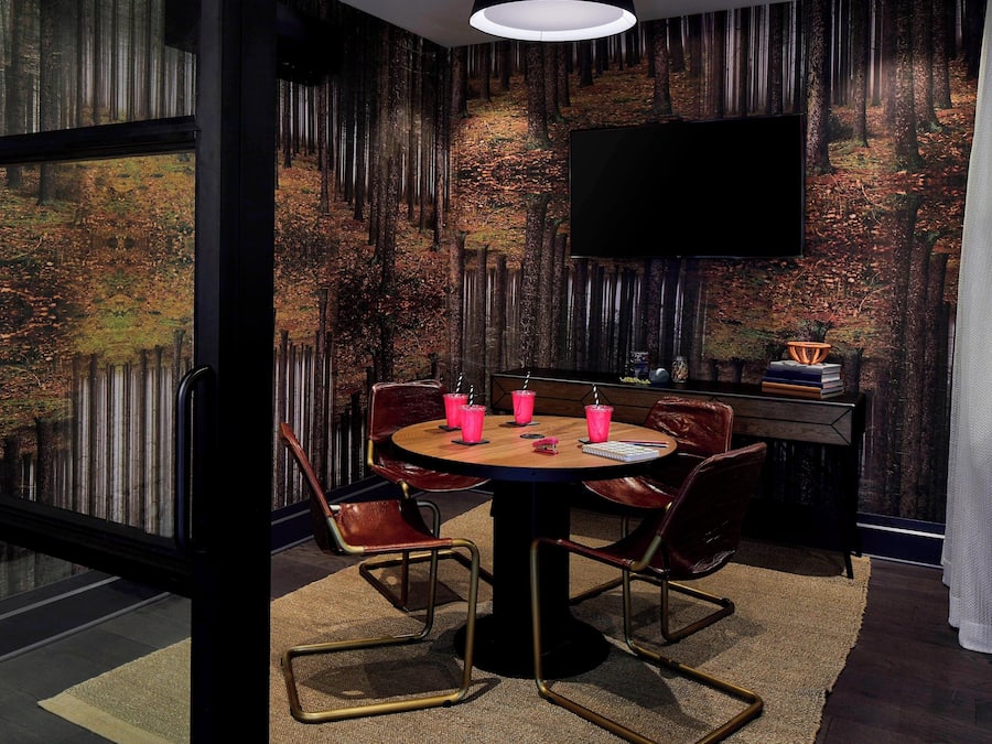 A modern dining area with a round table, chairs, and a television mounted on the wall.