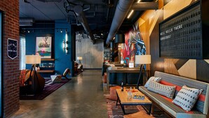 A modern lounge area with a sofa, coffee table, and a wall-mounted display. - Moxy Chattanooga Downtown (Chattanooga)