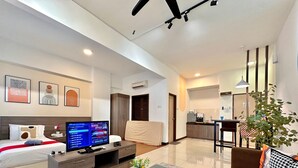 A modern hotel room with a bed, a TV, a desk, and a kitchenette.