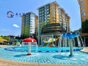 Een waterpark met glijbanen en fonteinen, omringd door meerlaags woongebouwen.