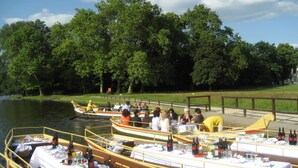 A riverside dining area with boats and tables set up for a meal. - Hotel Landhaus Wörlitzer Hof (Oranienbaum-Wörlitz)