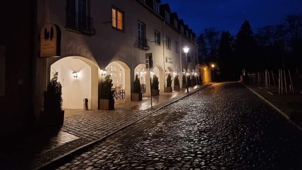 A building with arched entrances and a cobblestone street at night. - Hotel Landhaus Wörlitzer Hof (Oranienbaum-Wörlitz)