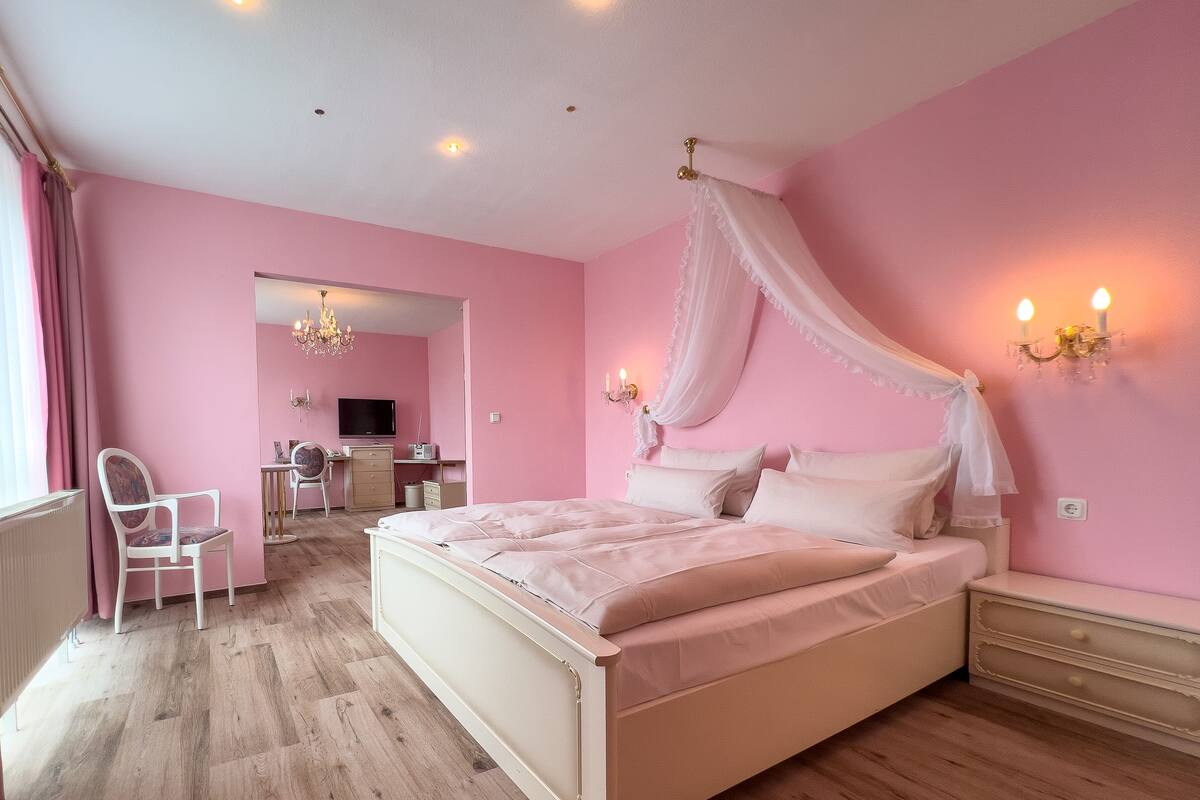 A bedroom with a large bed, a desk, and a chair.
