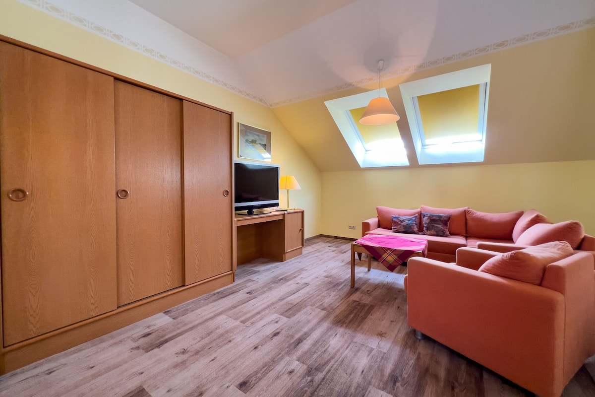 A cozy living room with a wooden wardrobe, a sofa, a TV, and a small table.