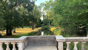 A stone bench with balustrades overlooking a calm waterway surrounded by lush greenery. - Hotel Landhaus Wörlitzer Hof (Oranienbaum-Wörlitz)