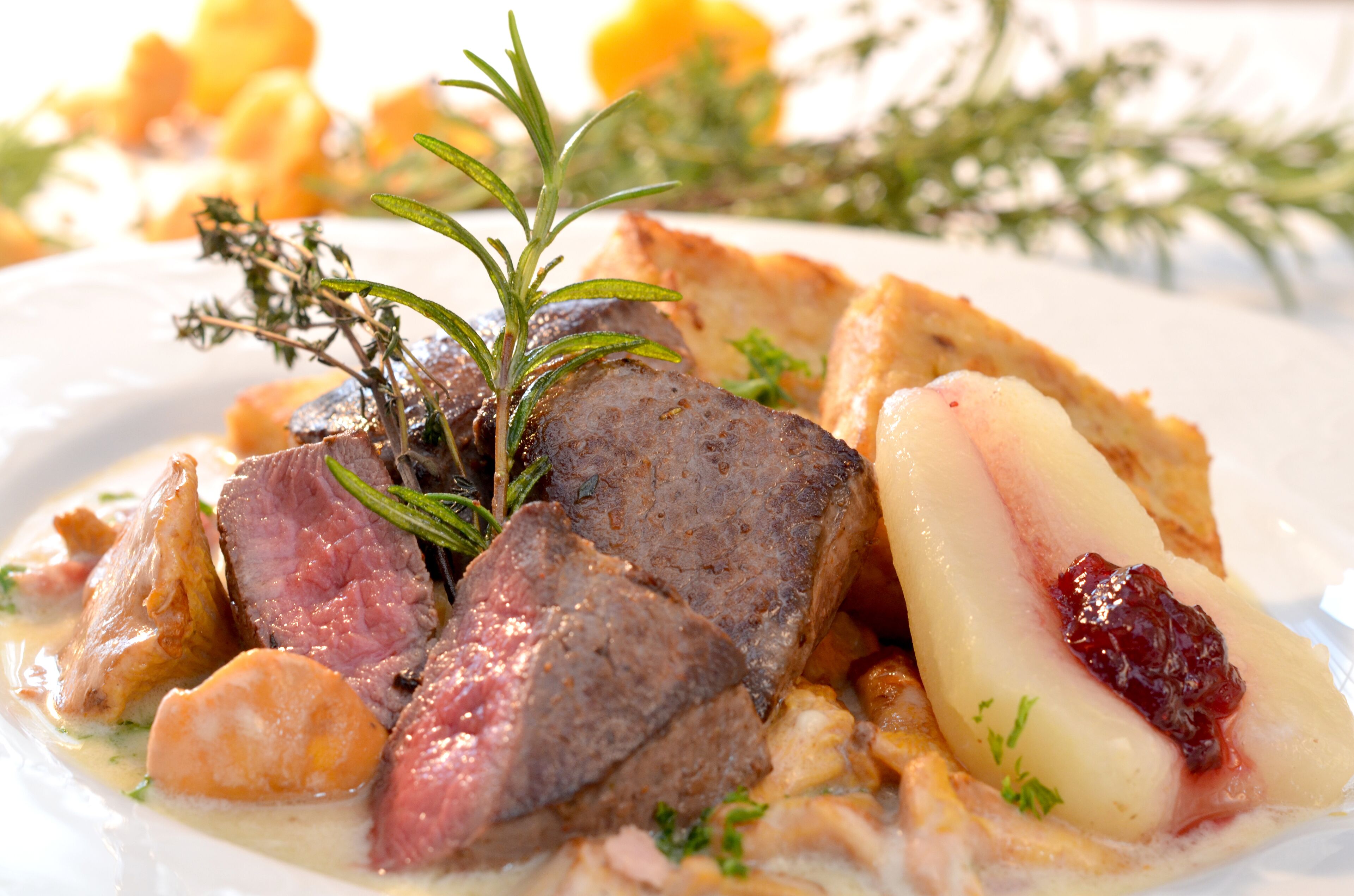 Prato com carne, batatas e um ramo de alecrim.