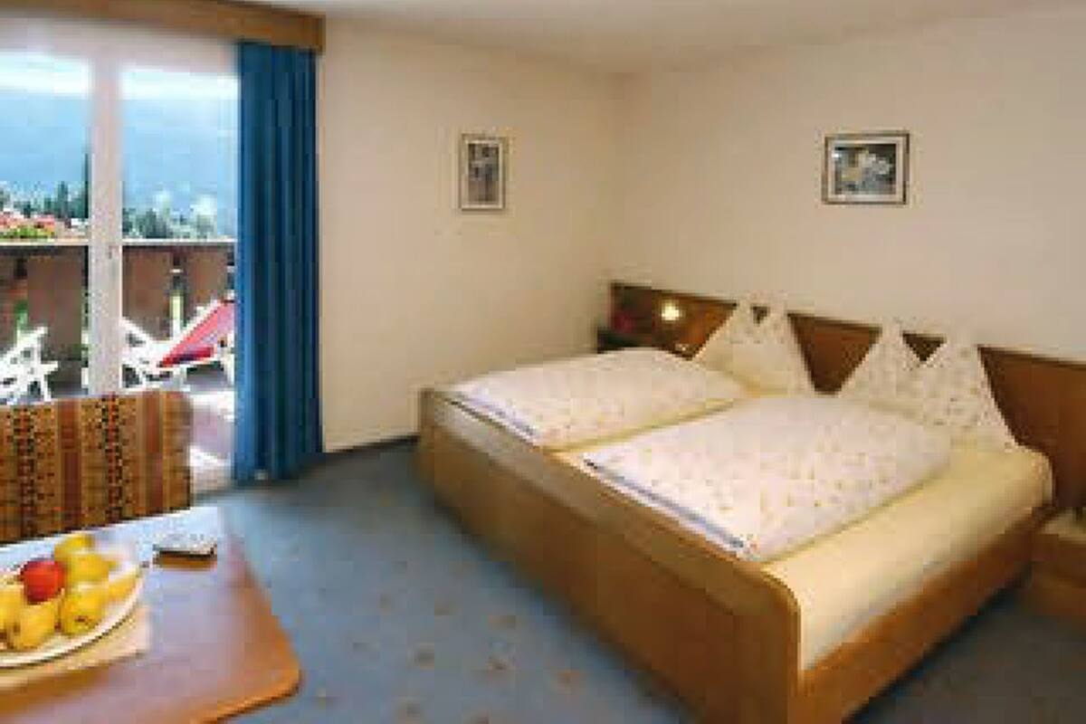 Une chambre d’hôtel avec un lit, une petite table avec des fruits et une vue sur l’extérieur.