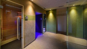A corridor with a wooden wall on the left, a green wall on the right, and a tiled floor. - Hotel Tirolerhof (Terento)