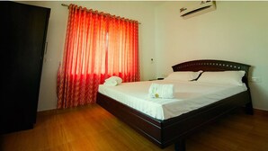 A neatly made bed with white linens, a wooden headboard, and a red curtain partially drawn to the side. - Magic Land Resort (Chalakudy)