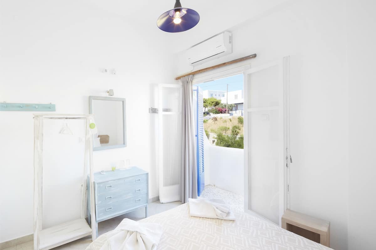 Un dormitorio con cama, cómoda, espejo y lámpara colgante.
