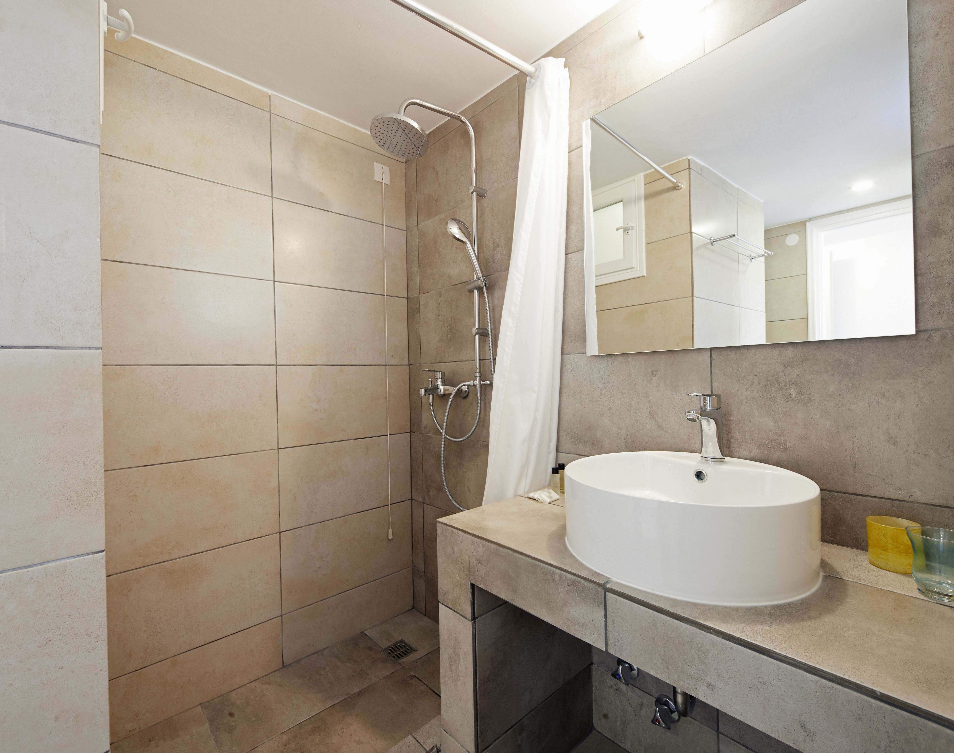 Un baño moderno con ducha, lavamanos y espejo.