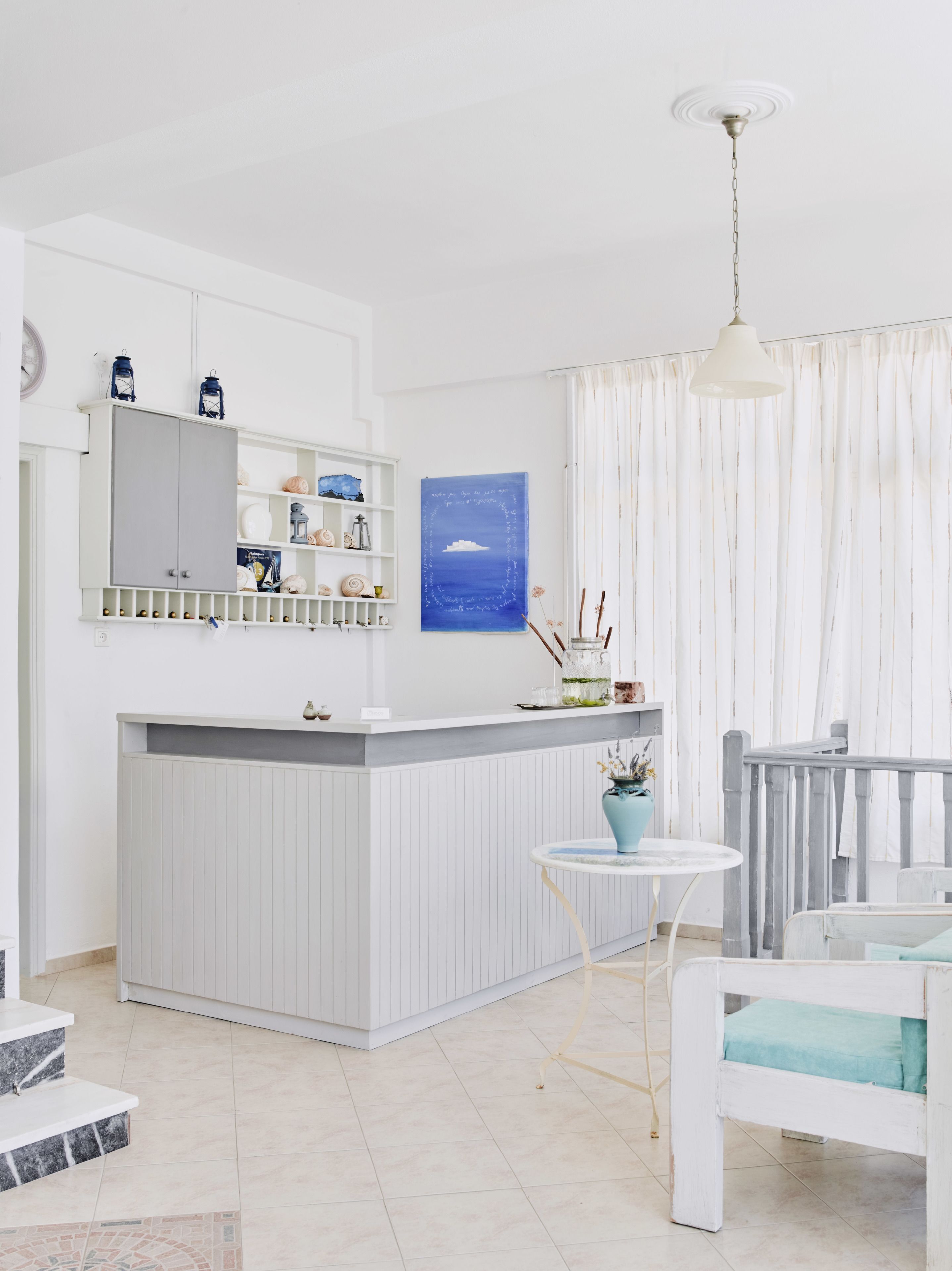 A modern kitchen with a white and gray color scheme, a built-in island, and a pendant light.