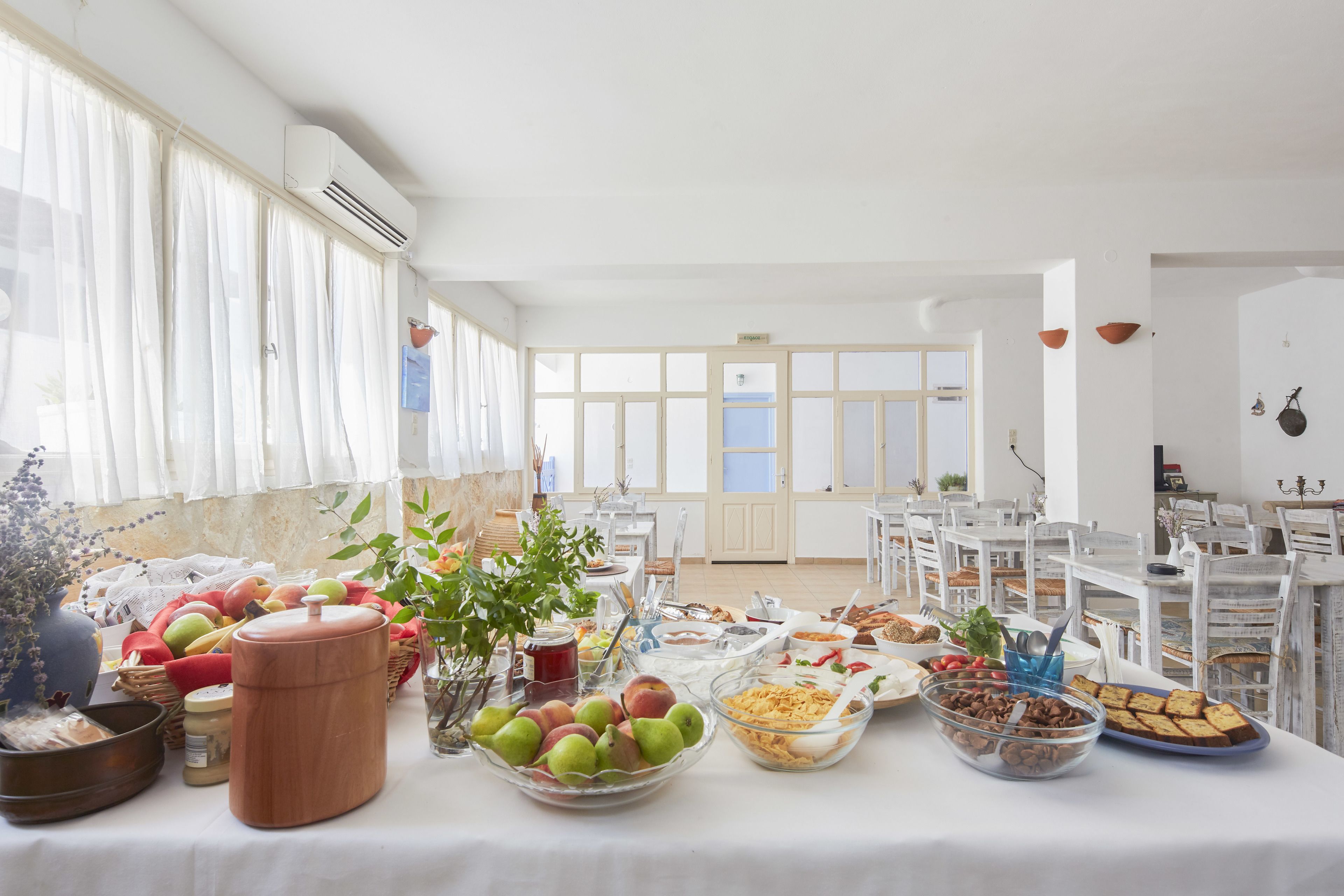 A breakfast buffet with various food items and a large window with curtains.