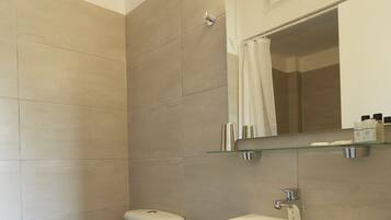 Un baño moderno con inodoro, lavabo y repisa de vidrio sobre el lavabo.