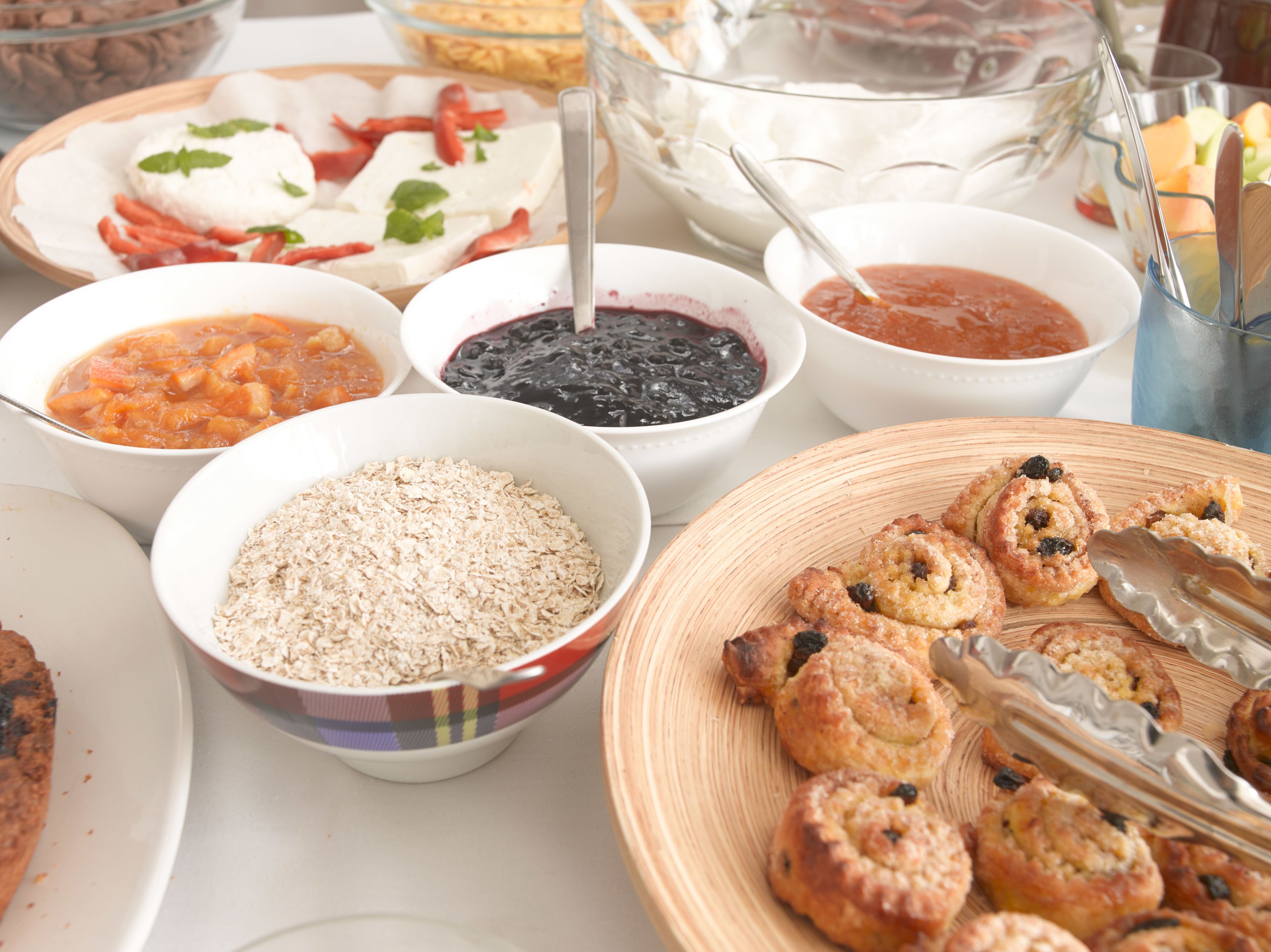A breakfast buffet with various dishes including oatmeal, pastries, and fruit.