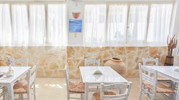 A dining area with stone walls, white tables, and wicker chairs.