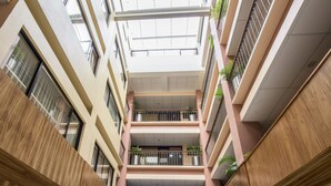 A multi-level atrium with wooden paneling and balconies, featuring a central open space and potted plants. - Hotel Oaxaca Inn Reforma (Oaxaca)
