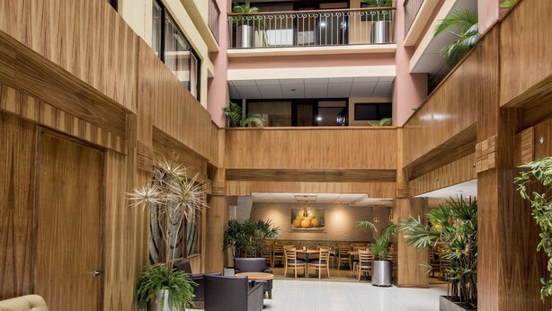 A multi-level atrium with wooden paneling, potted plants, and a central seating area with tables and chairs. - Hotel Oaxaca Inn Reforma (Oaxaca)