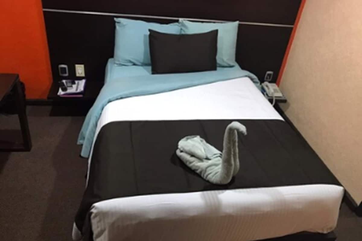 Et hotelværelse med en seng, et natbord og en telefon.