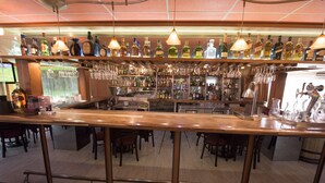 A bar area with multiple shelves of bottles and glasses, a wooden counter, and several chairs. - Hotel Oaxaca Inn Reforma (Oaxaca)