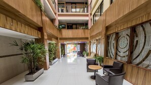 A spacious indoor atrium with a high ceiling, wooden paneling, and a central seating area with a round table and chairs. - Hotel Oaxaca Inn Reforma (Oaxaca)