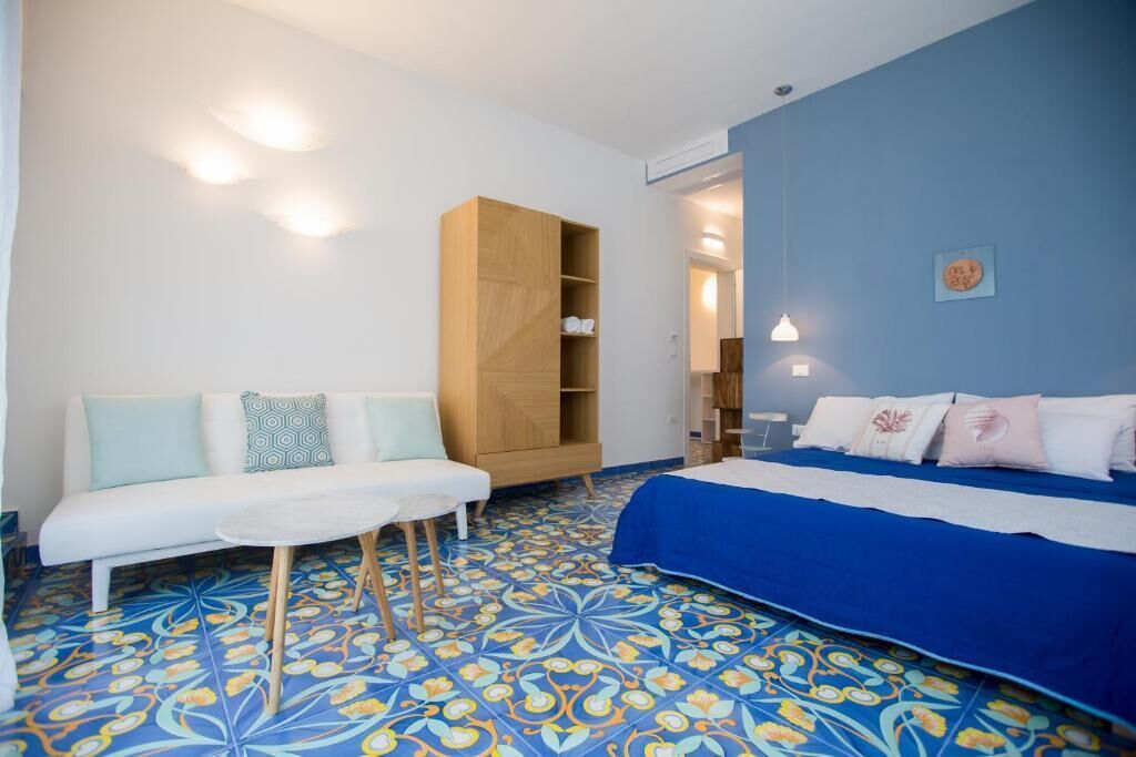 A room with a bed, a sofa, a small table, and a bookshelf.