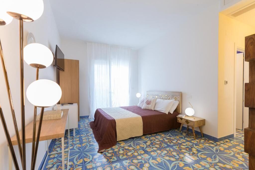 Un dormitorio con cama, mesita de noche, lámpara y un escritorio con silla.