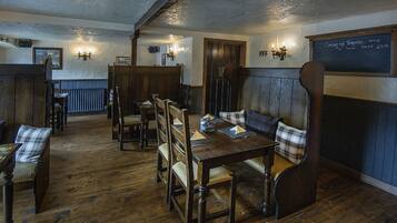 Interior de un pub tradicional con muebles de madera, un menú en la pizarra y un ambiente acogedor.