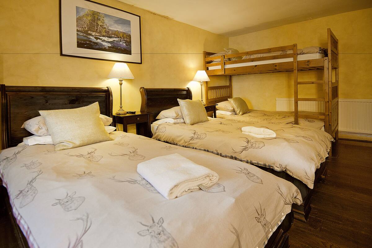 A hotel room with two beds, wooden headboards, and a bunk bed above.