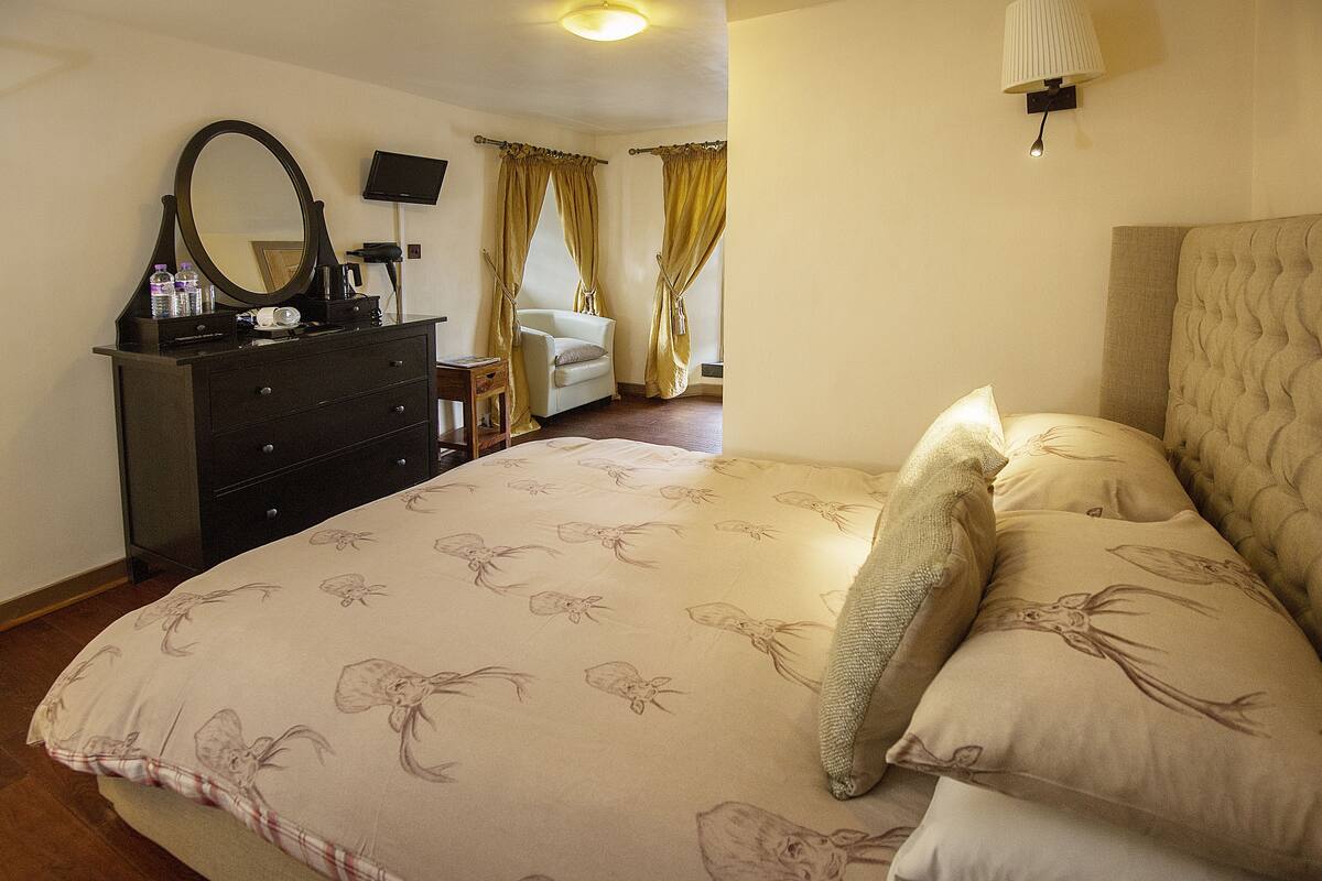 A bedroom with a bed, a dresser, a chair, a television, and curtains.