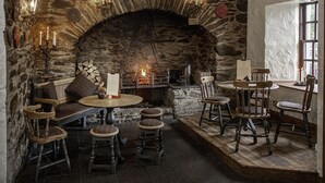 Un interior de paredes de piedra con chimenea, muebles de madera y apliques de velas.