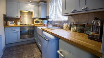 Una cocina moderna con armarios azul claro, encimera de madera y electrodomésticos de acero inoxidable.
