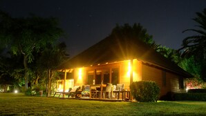 A house with a porch, outdoor seating, and a well-lit garden at night. - Playa Montroig Camping Resort (Mont-roig del Camp)