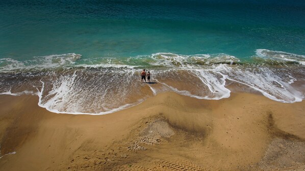 Vista aérea de una playa con dos personas cerca de la orilla.