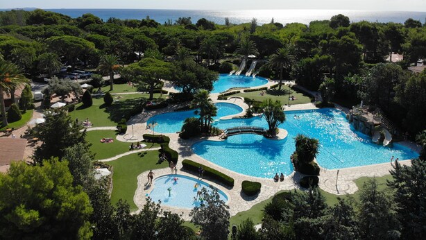A resort with multiple swimming pools, lush greenery, and a view of the sea. - Playa Montroig Camping Resort (Mont-roig del Camp)