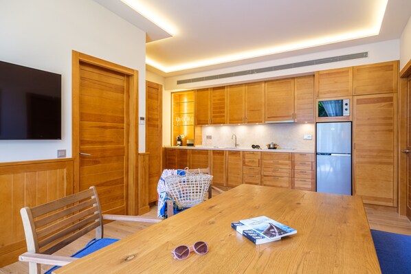 Una cocina moderna con armarios de madera, microondas integrado y refrigerador de acero inoxidable.