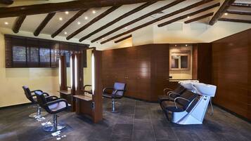 Experience a warm and inviting atmosphere in this stylish salon, featuring comfortable hairdressing chairs with hairdryers and polished tile floors.