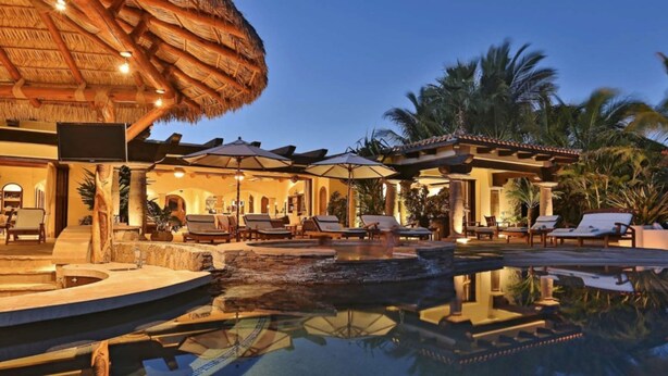 Un resort con piscina, sillas de descanso y una estructura de techo de paja.