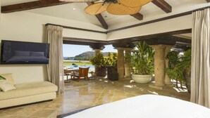 Un dormitorio amplio con una cama grande, un televisor montado en la pared y vistas a una piscina y montañas.