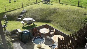 A patio area with outdoor seating, a water feature, and a view of a grassy field with sheep. - The Anchorage (Amlwch)