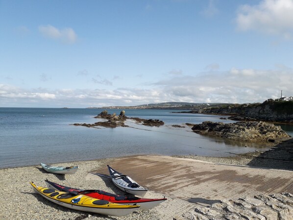 Una playa con kayaks y un litoral rocoso.