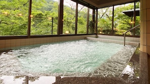 Een hottub met uitzicht op weelderige begroeiing en bergen.
