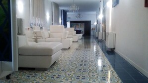 Un pasillo con piso estampado, sofás blancos y una araña.