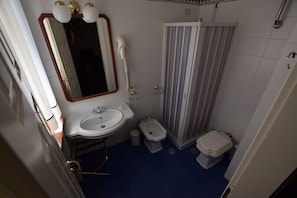 A small bathroom with a sink, mirror, bidet, toilet, and shower curtain. - Hotel Residenza Villa Duse (Gioia del Colle)