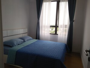 A bedroom with a bed, curtains, and a window.